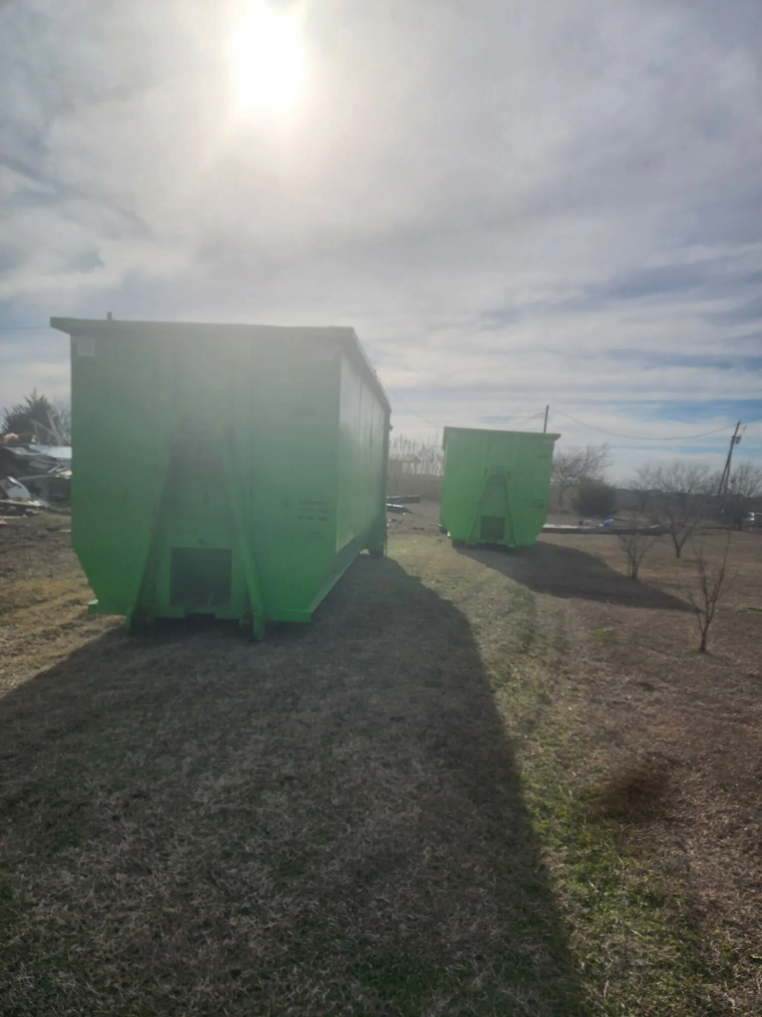 Green roll-off dumpsters on site for a large junk removal and demolition project in DFW