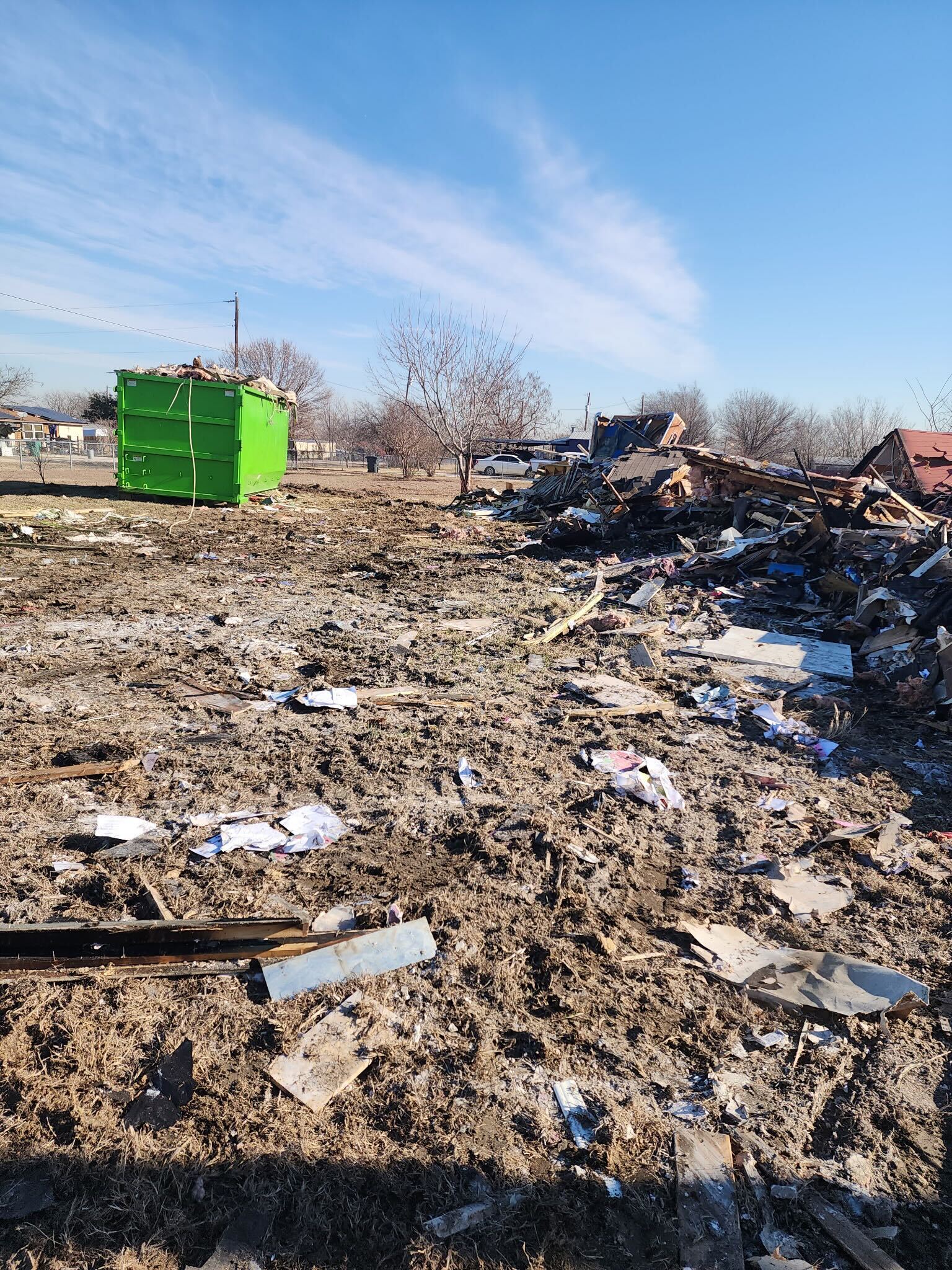 Demolition site with green dumpster showing BlackIron Hauling cleanup progress in DFW